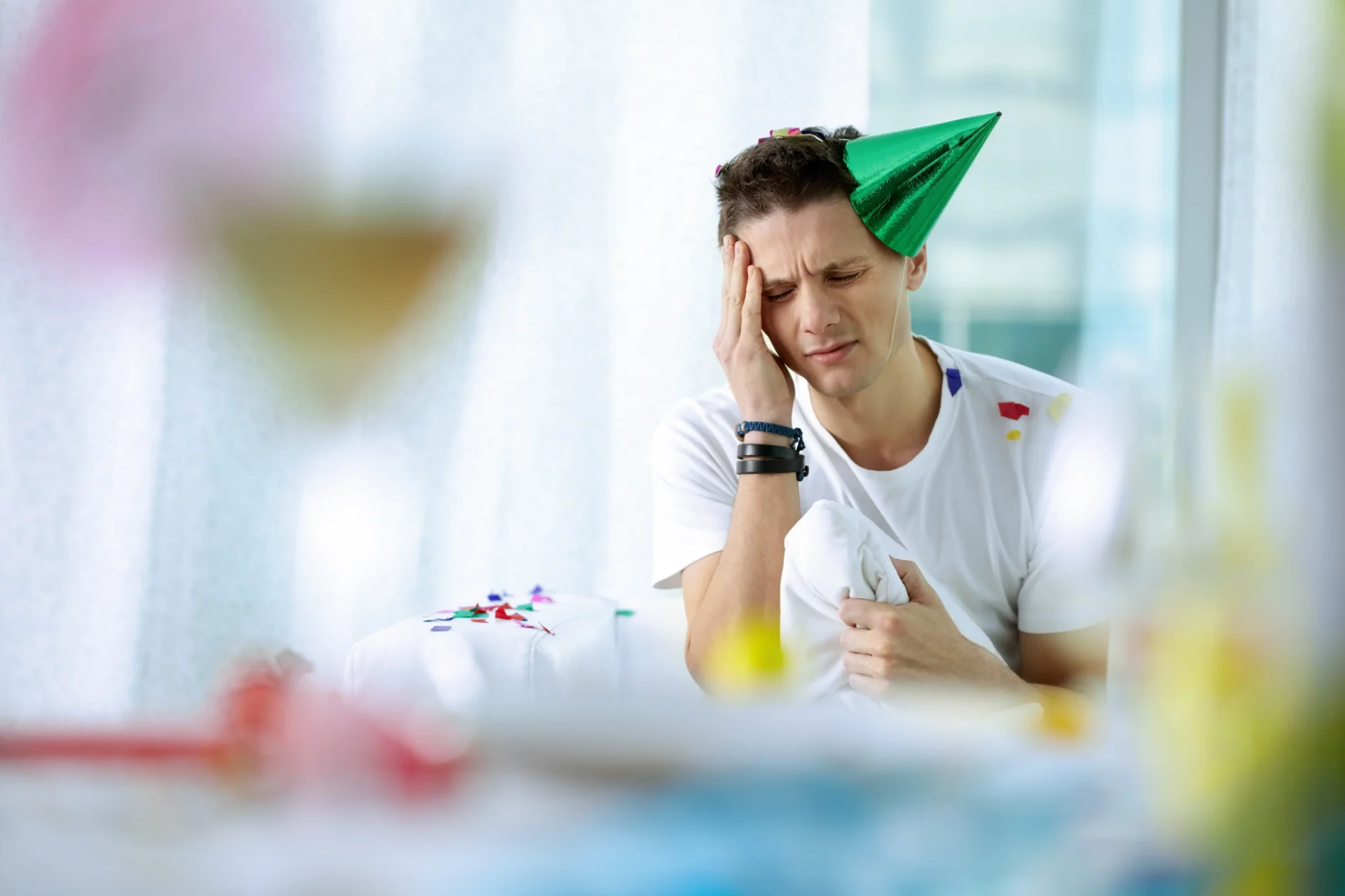 Man holding his head with a hangover headache the morning after a party
